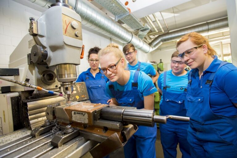 Head of training with apprentices at the machine – four women and one man, 2016