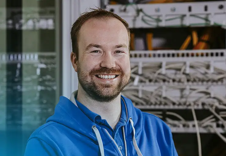 Pieron employee smiling in front of a server cabinet in the IT department
