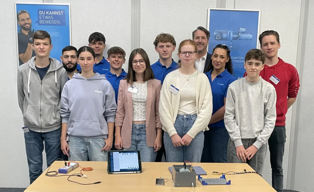 Group of participants in the Schüler macht MINT campaign in front of roll-up banners and an experiment table