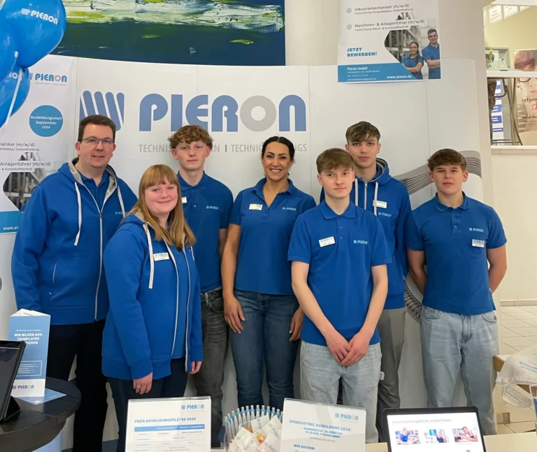 Group in Pieron jackets at the fair stand with roll-up banner and information material